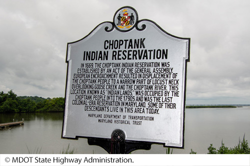 Historical roadway marker inscribed with, “In 1669, the Choptank Indian Reservation was established by an act of the General Assembly. European encroachment resulted in displacement of the Choptank People to a narrow part of Locust Neck overlooking Goose Creek and the Choptank River. This location, known as “Indian Lands,” was occupied by the Choptank People into the 1790s and was the last colonial-era reservation in Maryland. Some of their descendants live in this area today.” Image Source: © MDOT State Highway Administration.