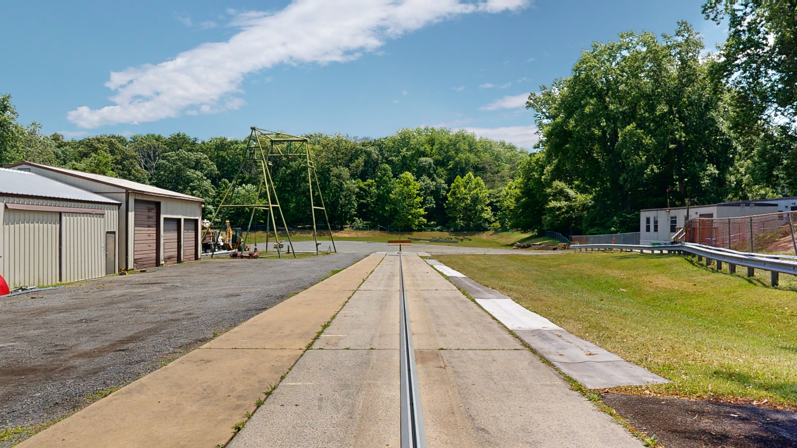 A long track with a mechanized system to propel test cars in an outdoor testing area.  