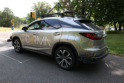 A CARMA℠-branded vehicle at an intersection shows a driver-side view of equipment installed to support self-driving functionality.