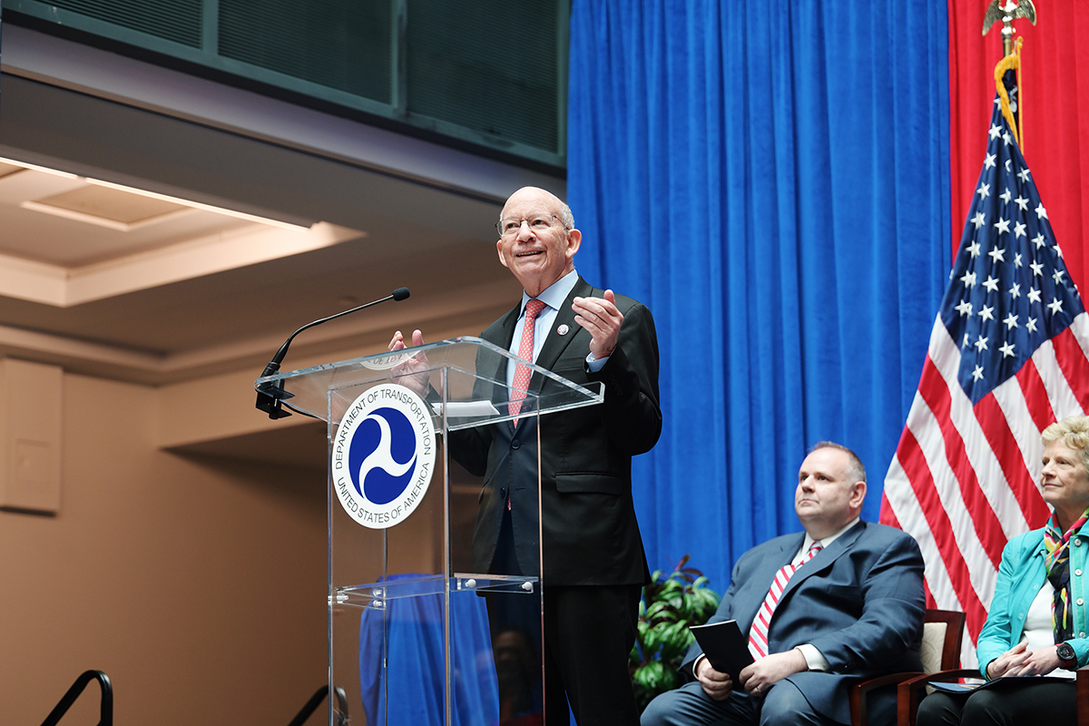 Former Representative Peter DeFazio speaking from the podium. Assistant Secretary Philip A. McNamara and Administration Robin Carnahan of the General Services Administration look on.