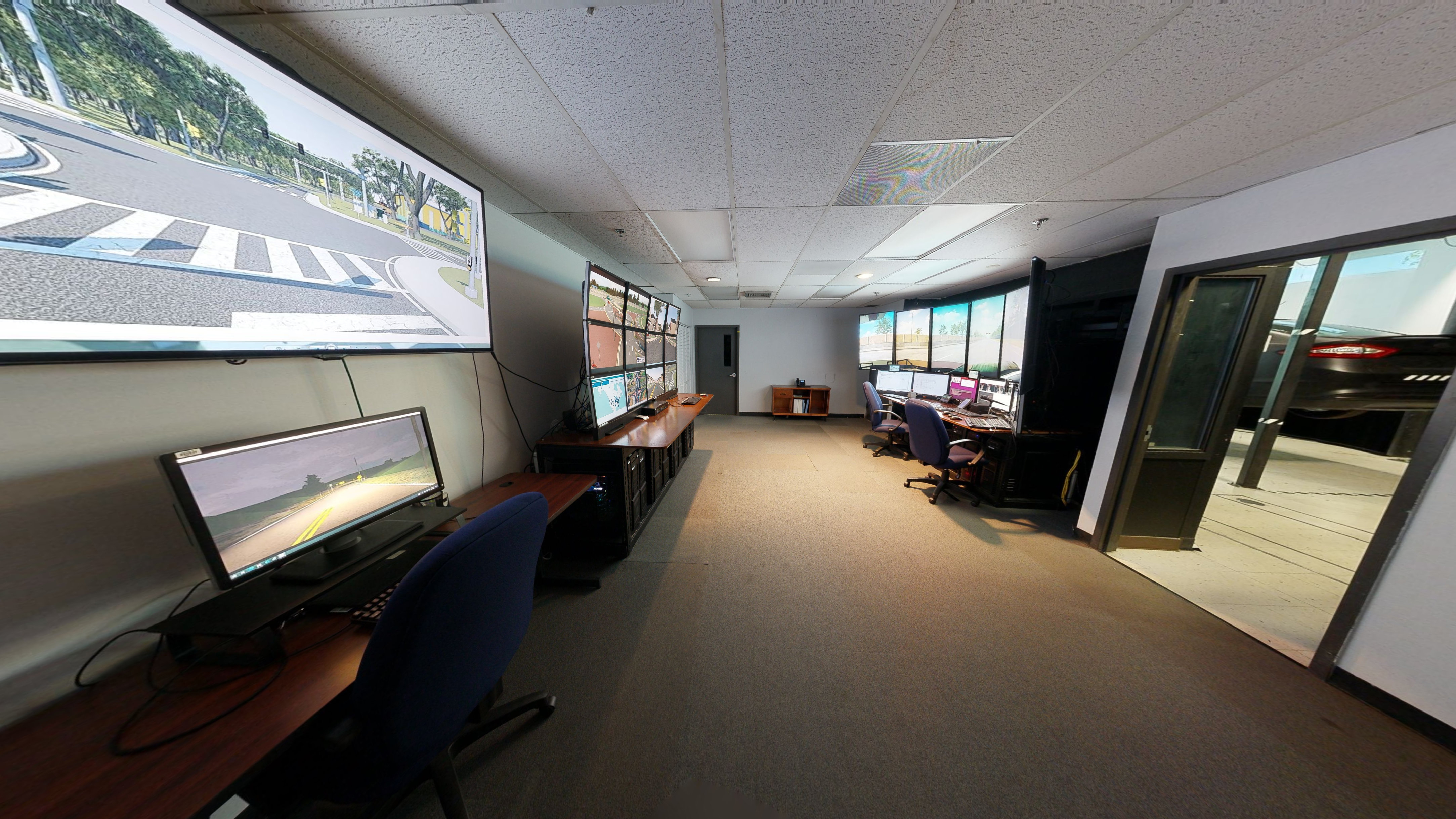 A room is set up with several desks containing multiple screens at each one.  