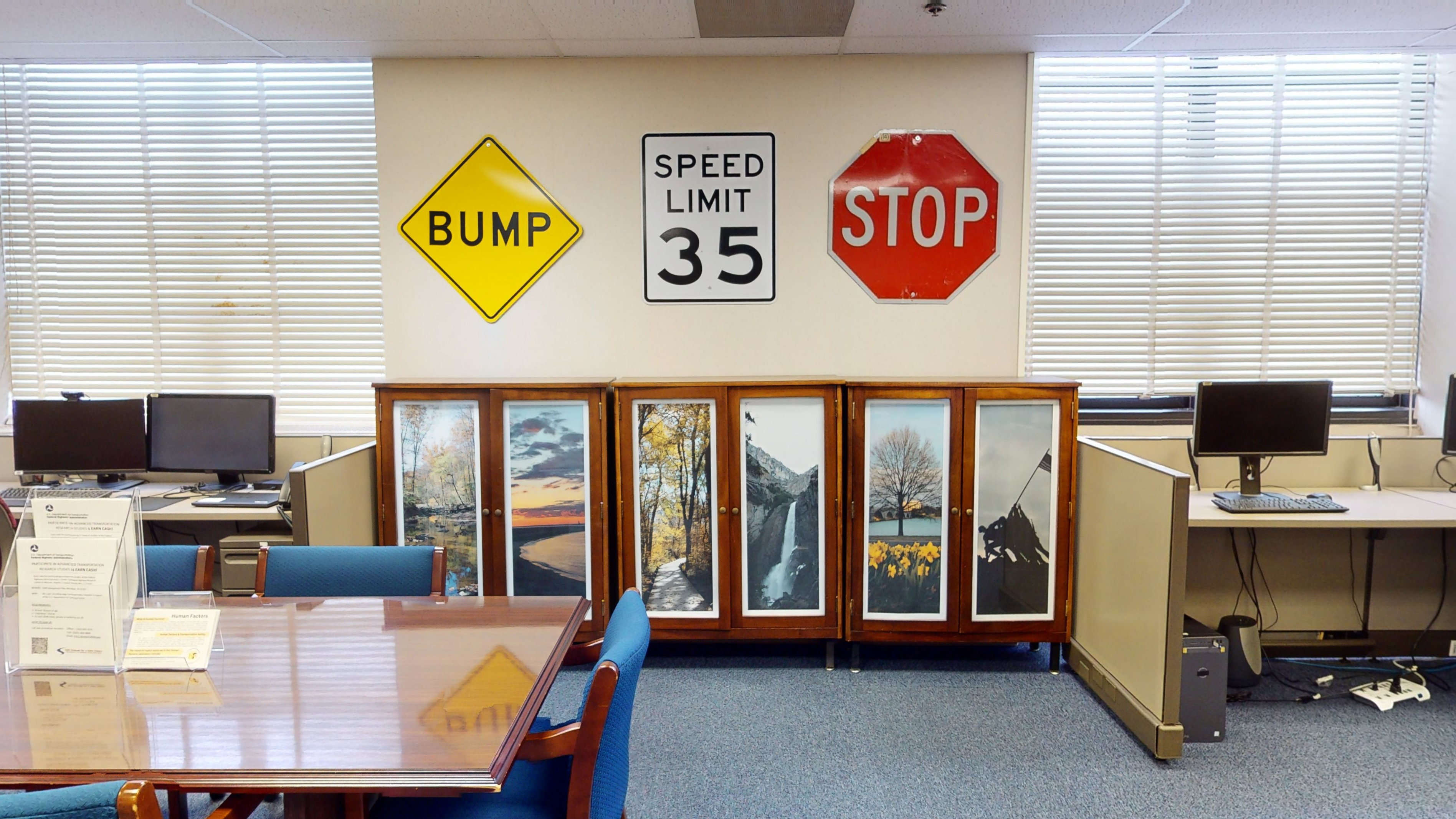 Cabinets in an office flanked by computer workstations below traffic signs.