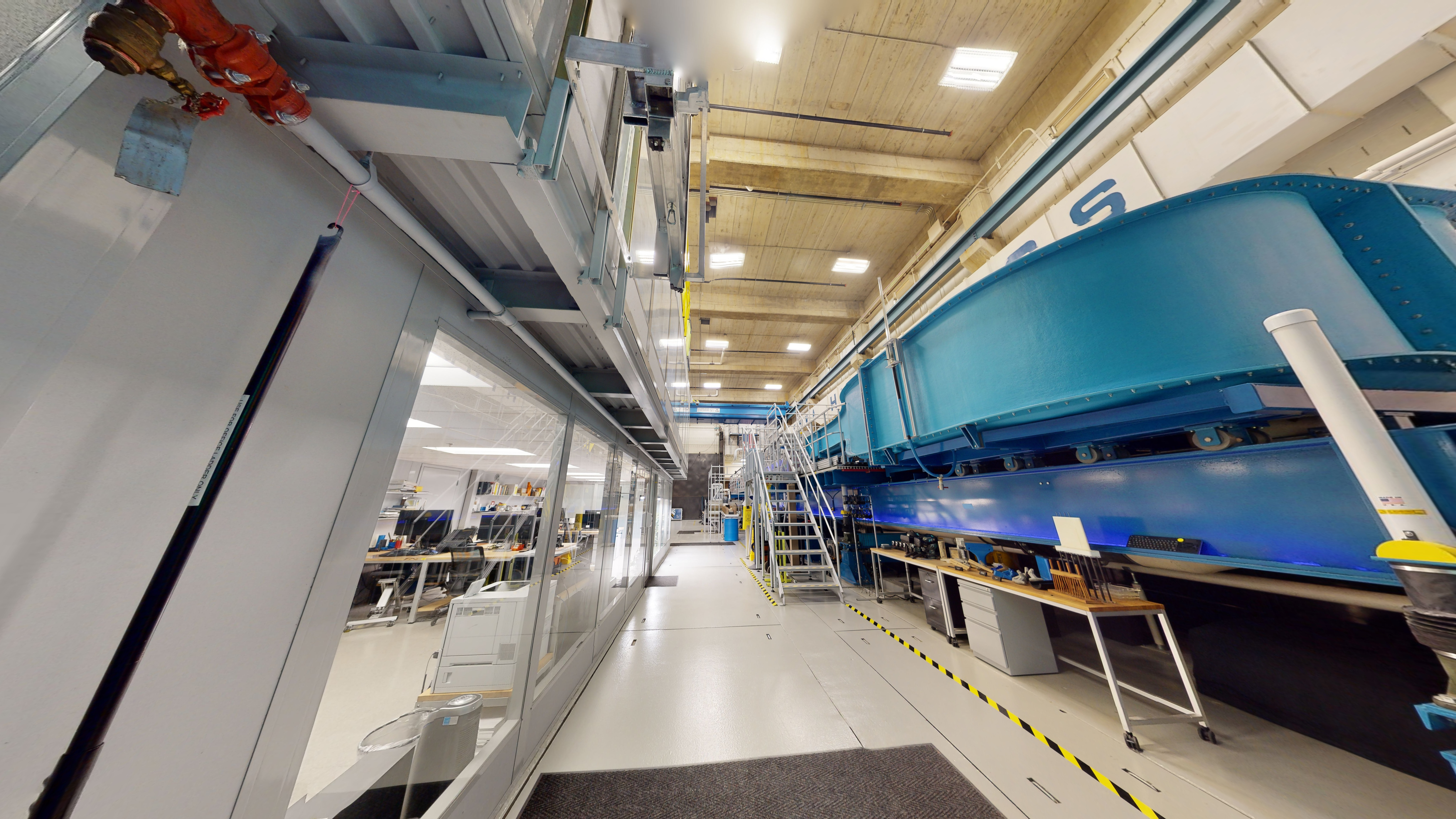 Ground floor of a laboratory with computer workstations on the left and a flume on the right. 