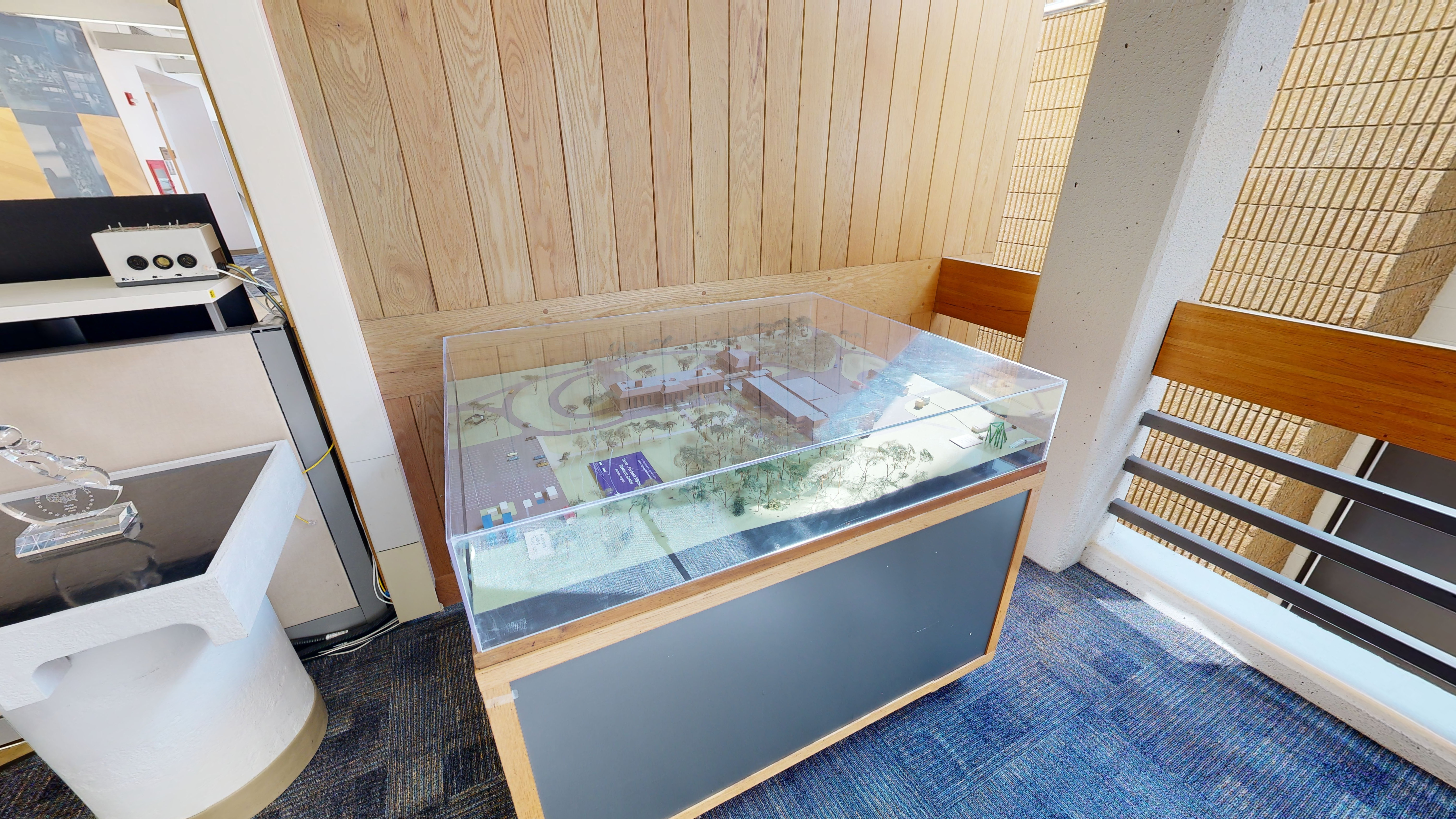 A closeup of two displays: A glass trophy on a table and a three-dimensional model. 