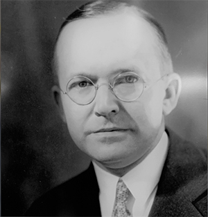 Historical black and  white photograph of Herbert S. Fairbank—a middle aged white man with round glasses in a dark suit and tie.