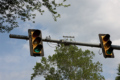 Two traffic lights flank various mounted equipment on the horizontal arm of a pole. 