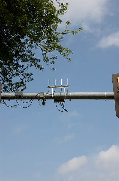 A closeup view of the various mounted equipment on the horizontal arm of a traffic light pole. 