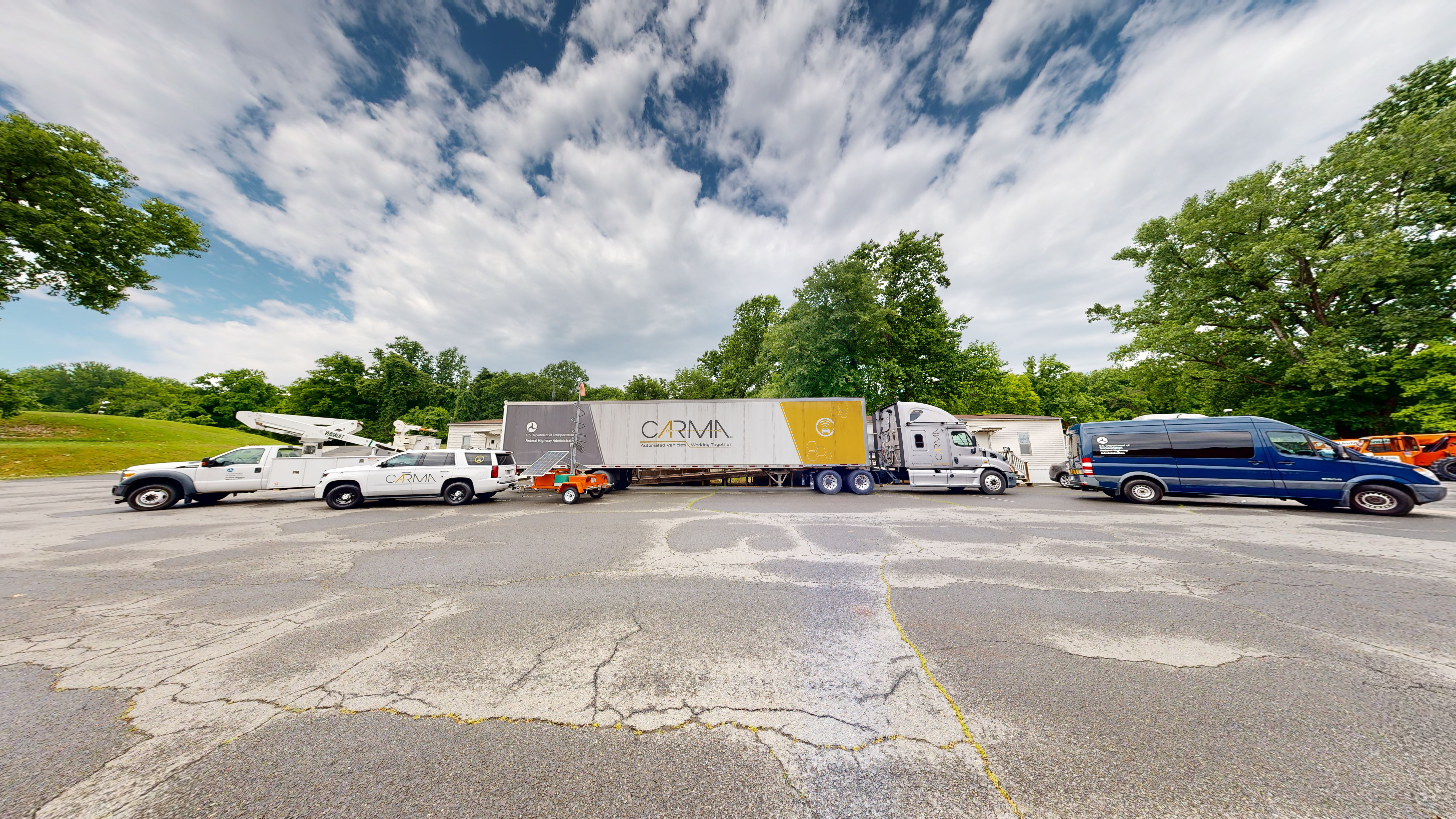 Several vehicles parked near each other in an outdoor concrete-covered area.