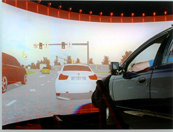 A car chassis in front of a screen displaying a virtual highway environment.