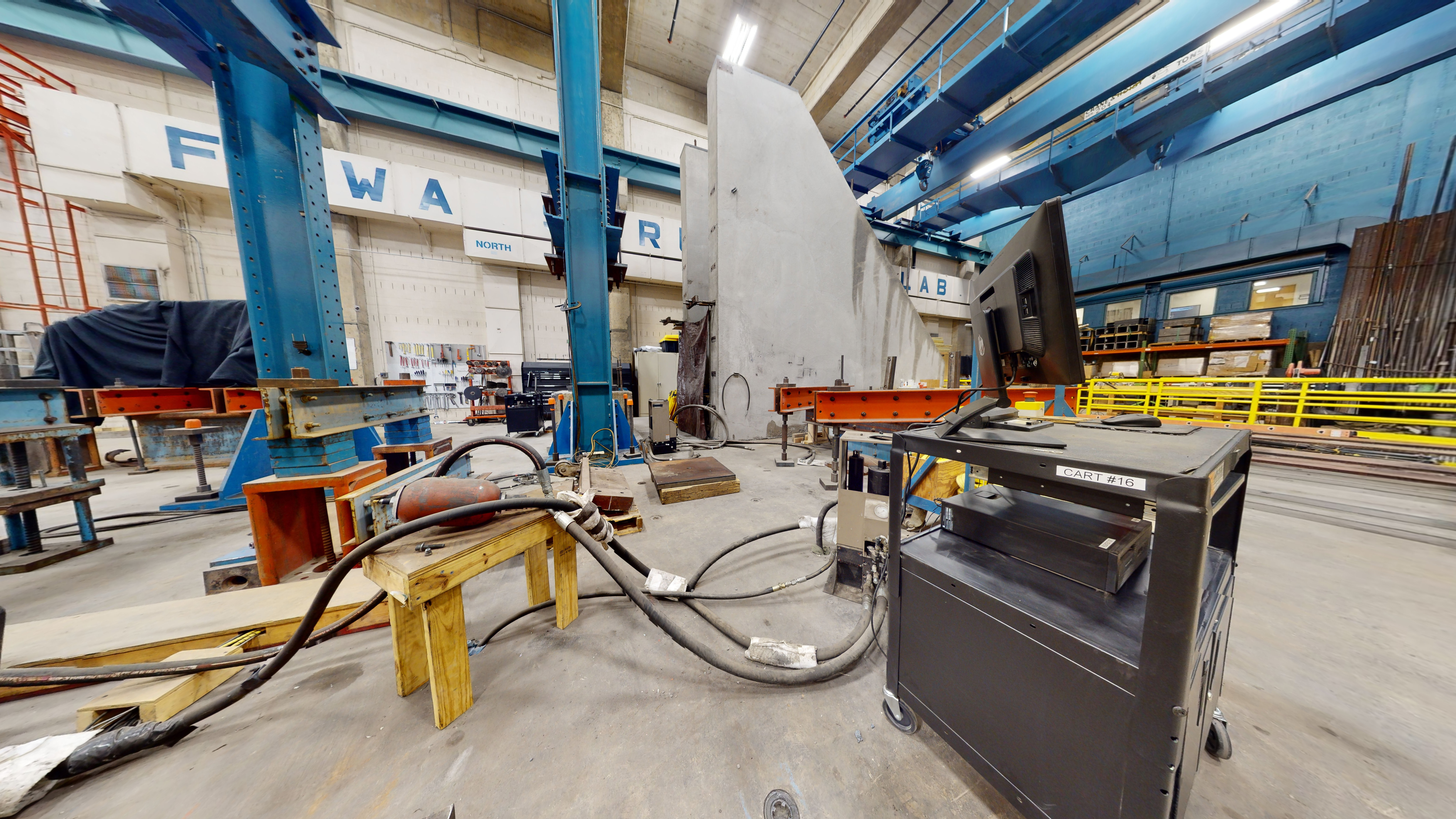 Laboratory space filled with an assortment of equipment for testing the performance of bridge structures and structural systems, including the large-scale beam static testing frame and high-force vertical load frame.  