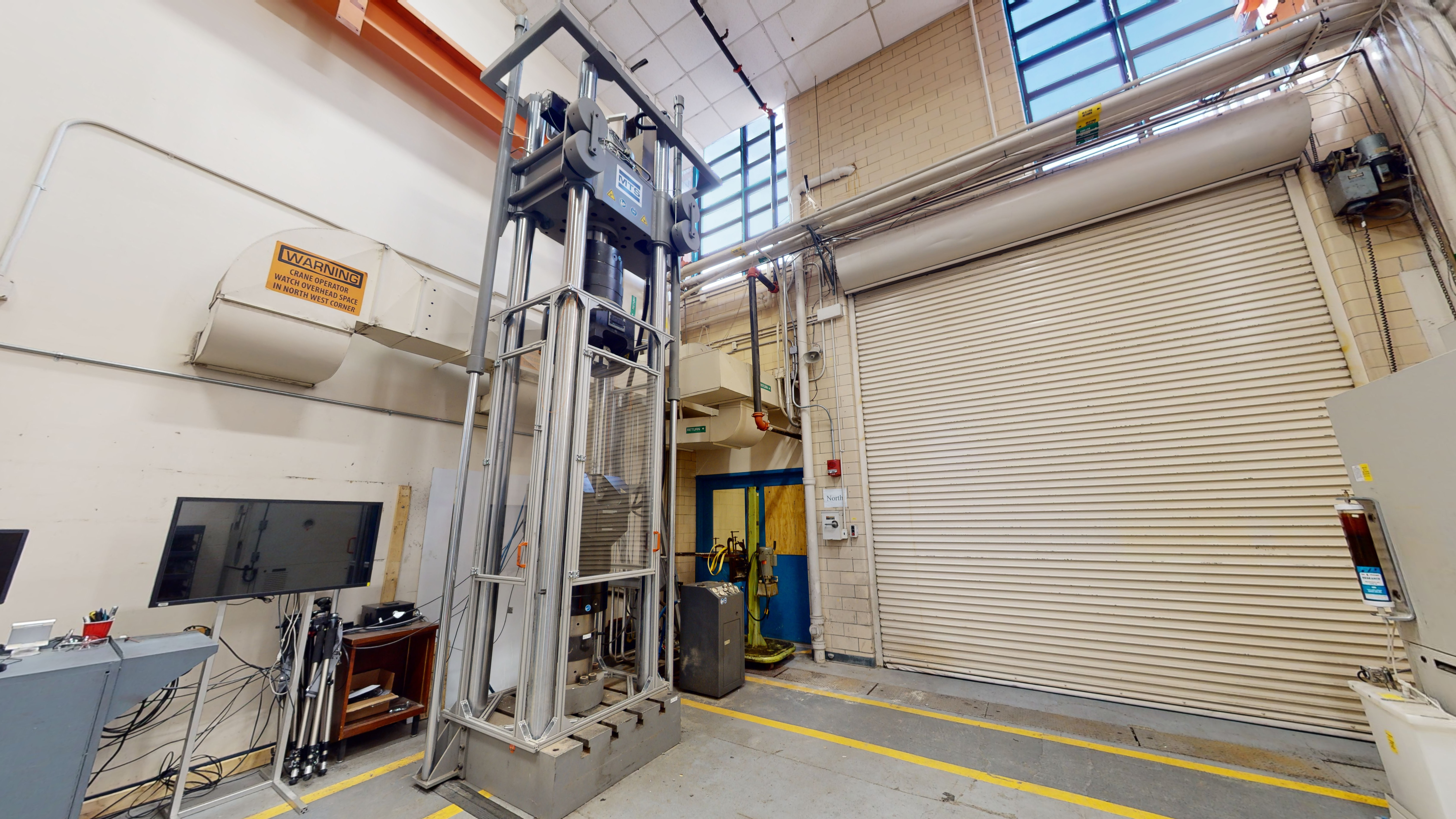 Part of a laboratory space with a capacity testing machine next to a stand-mounted monitor.