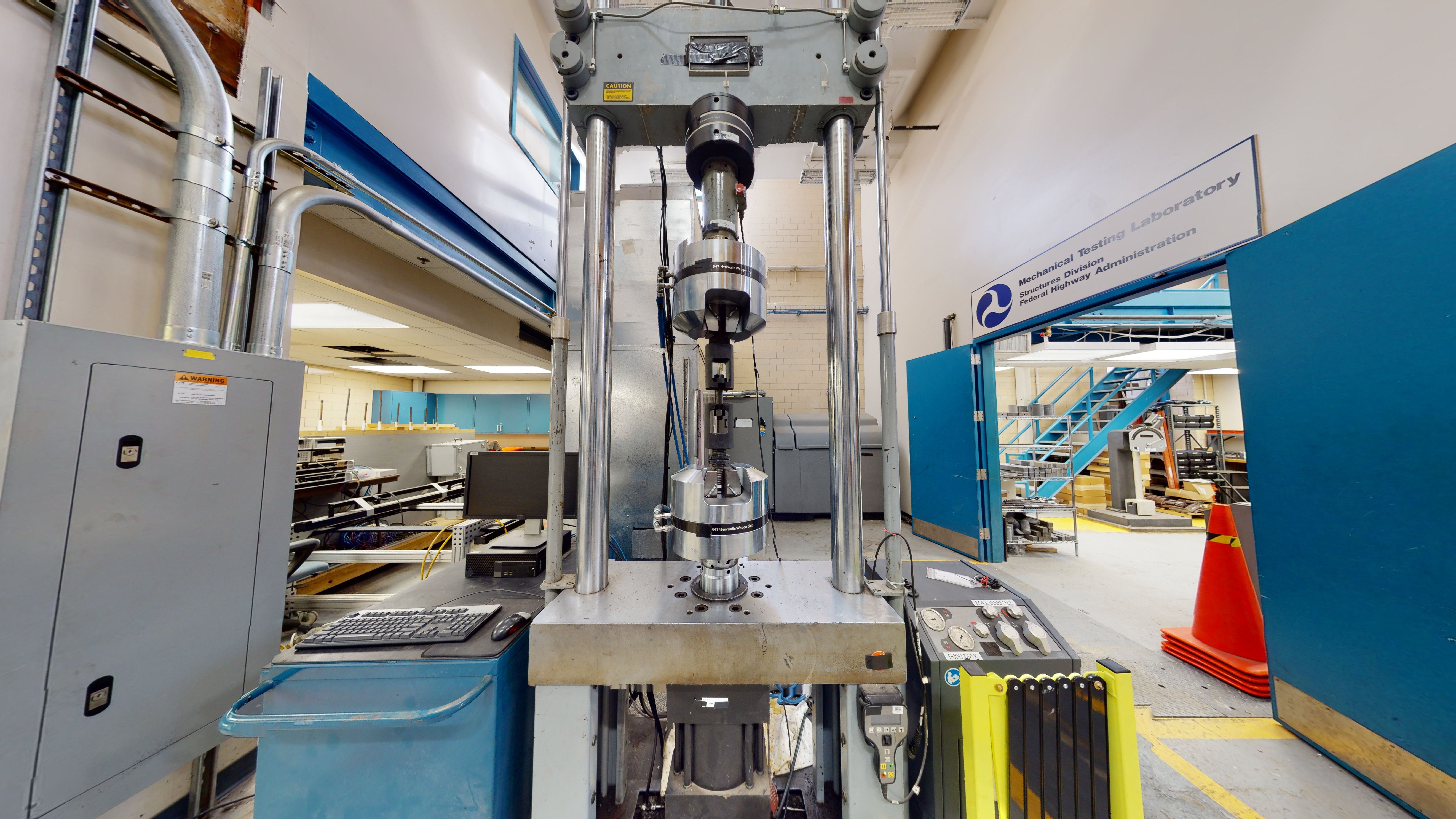 Part of a laboratory space containing a static and fatigue loading test machine next to a computer workstation.