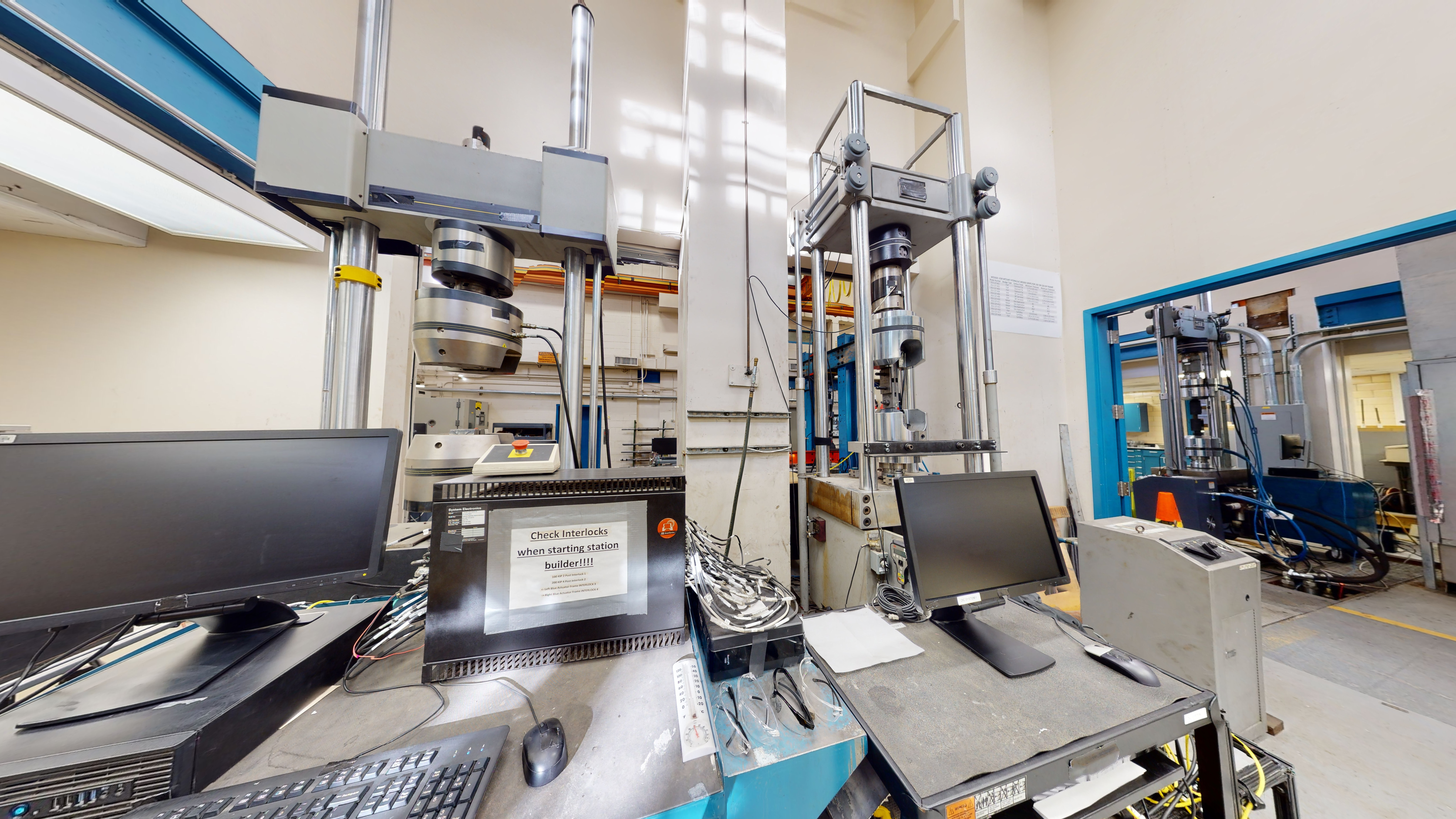 Part of a laboratory space with a static and fatigue loading test machine in front of computer workstations.