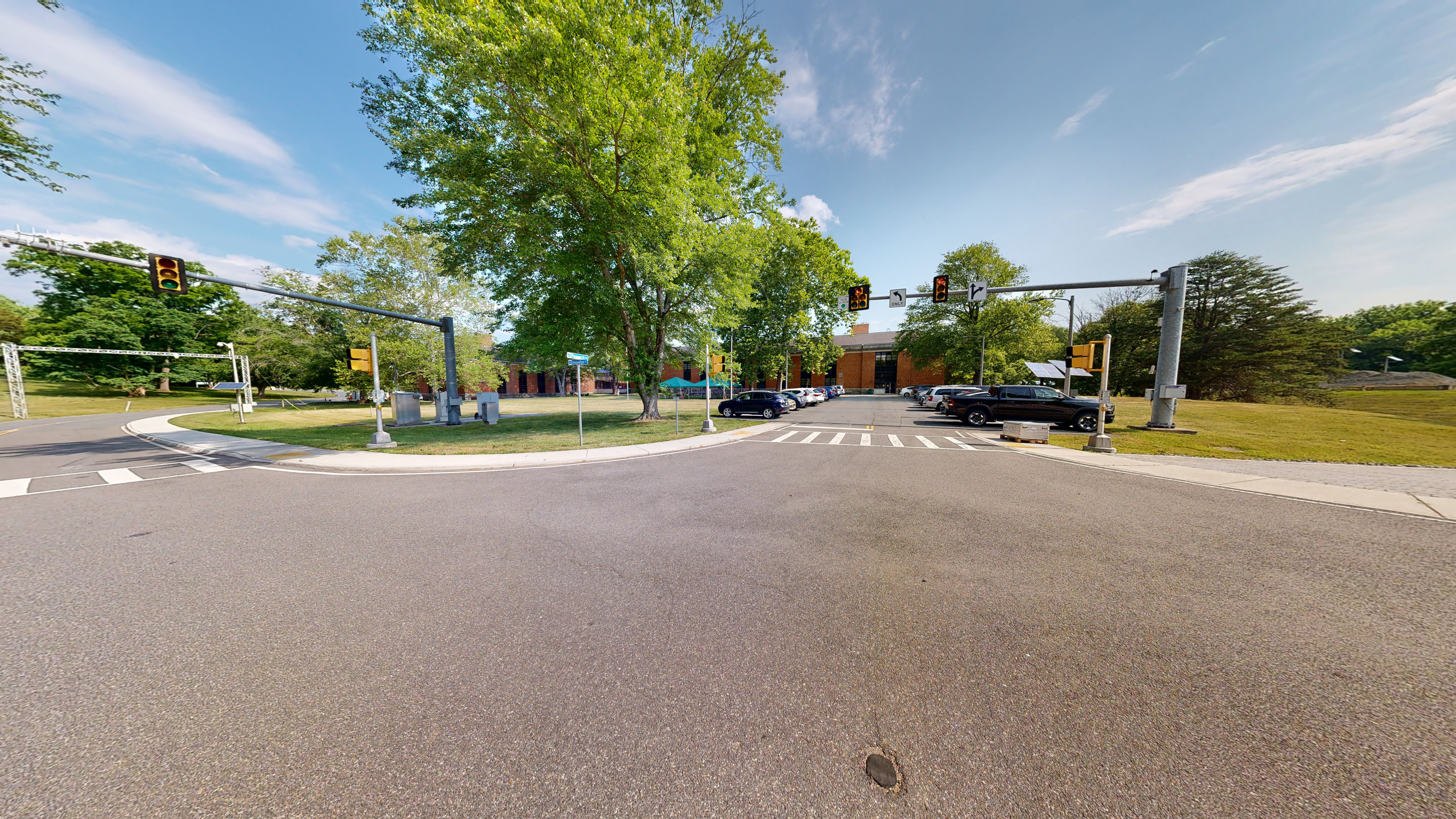 A street intersection with traffic and pedestrian signals on poles and crosswalks.