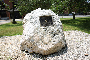 A large  rock with a metal plaque on it.