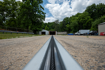 A closeup of the propulsion system track with a twisted metal rope facing a garage. 