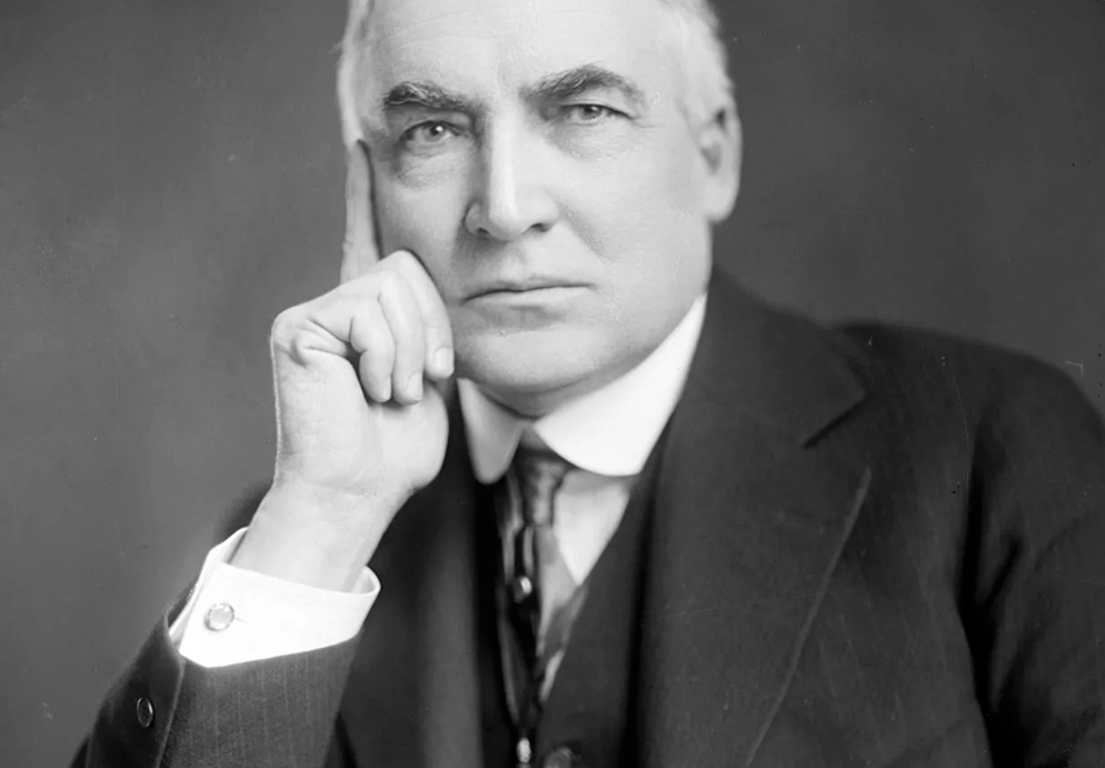 Portrait of Senator Harding in a suit and tie, resting his head on his hand, gazing forward with a neutral expression against a plain background.