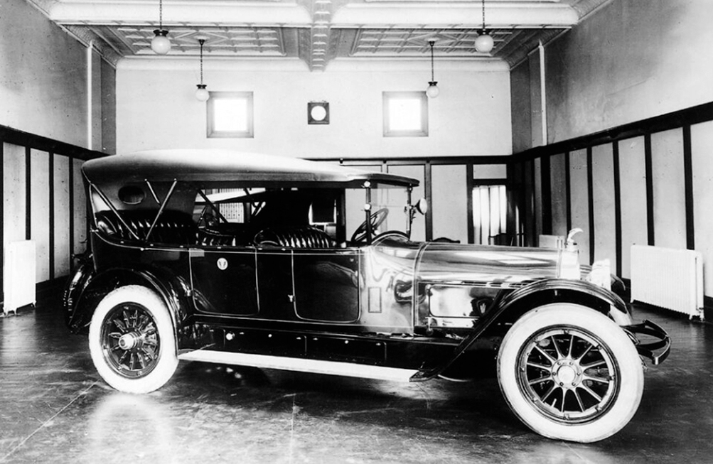 Senator Harding's locomobile, which appears to be a vintage black touring car, in a spacious indoor garage with decorative walls and large windows.