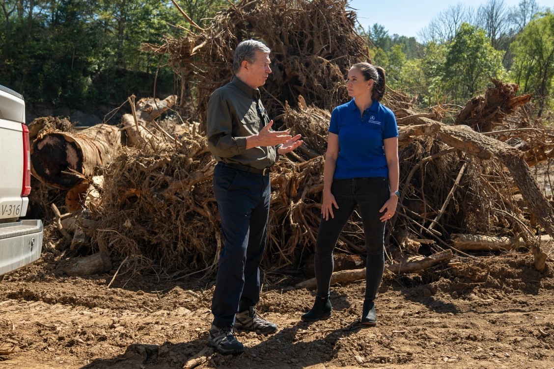 Kristin White and Roy Cooper conversing while standing in front of large fallen tree